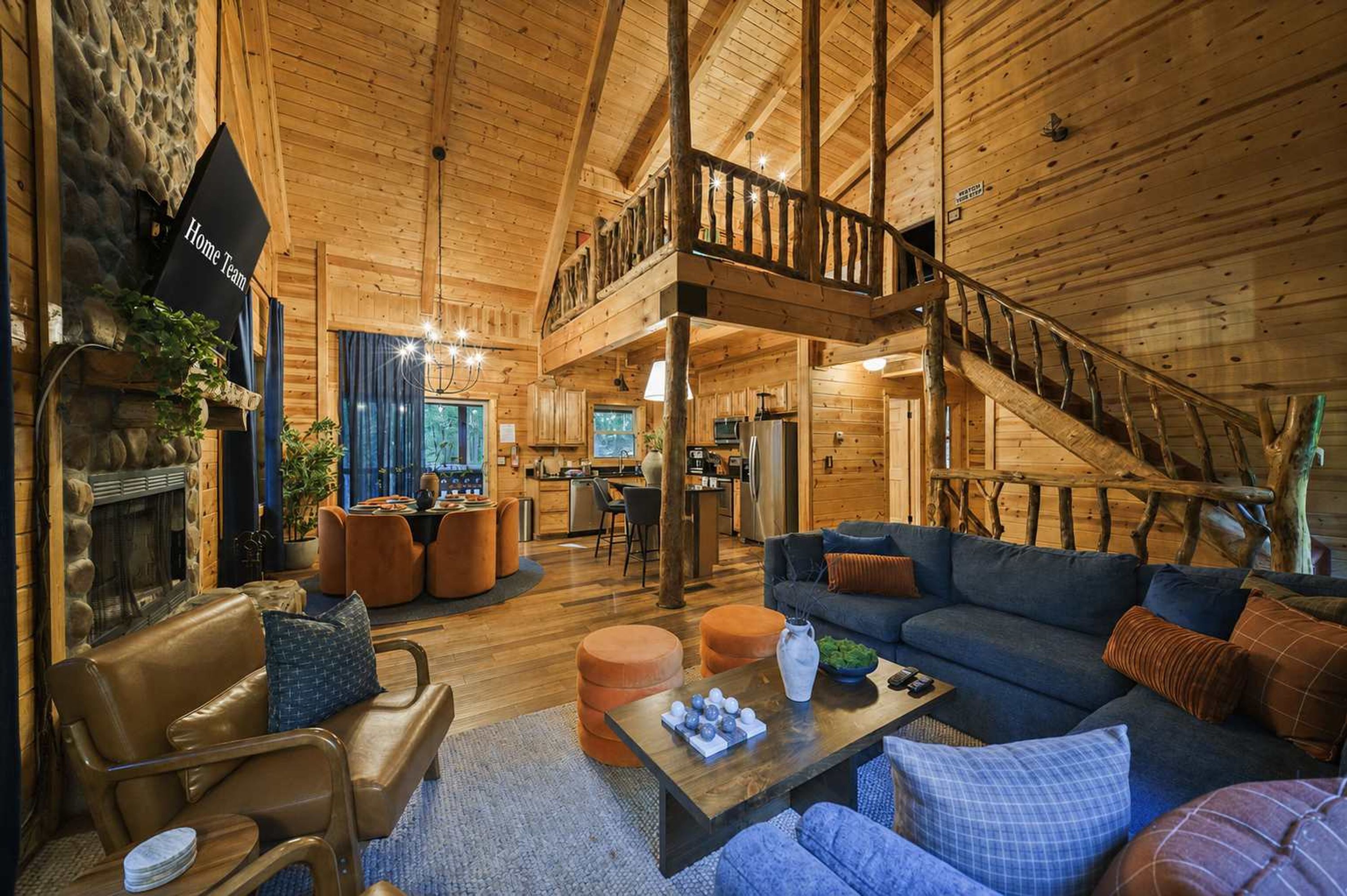 A spacious living area with a high ceiling, wooden beams, a fireplace, and a dining area with modern furniture.