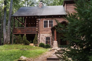A rustic log cabin with a porch, stone foundation, and a chimney. - The Hocking House Hot Tub Fire Pit Games (Logan)