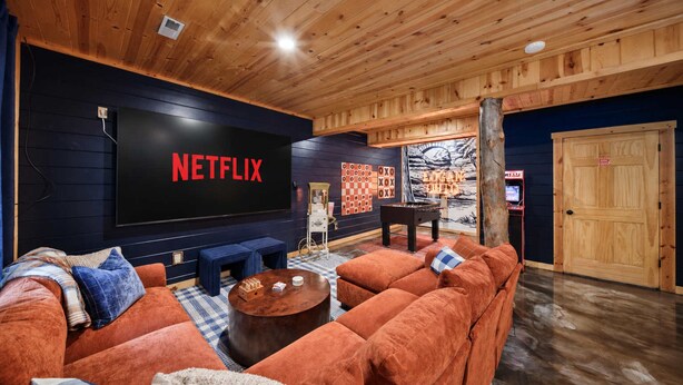 Una sala de estar acogedora con un televisor de pantalla plana grande, una mesa de fútbol y un sofá cómodo.