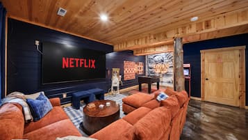 A cozy living room with a large flat-screen TV, a foosball table, and a comfortable sofa.