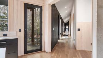 Un interior moderno con piso de madera, una zona de cocina con mostrador y vista a una terraza exterior a través de una puerta de vidrio.