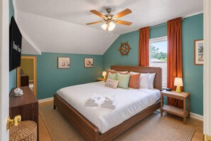A bedroom with a bed, a ceiling fan, a window with curtains, and a wall-mounted TV. - 4BR Emerald Coast Escape Pool Hot Tub Theater (Fort Walton Beach)