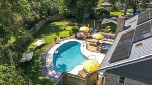 Un jardin avec une piscine, un jacuzzi et un espace patio agrémenté de parasols.