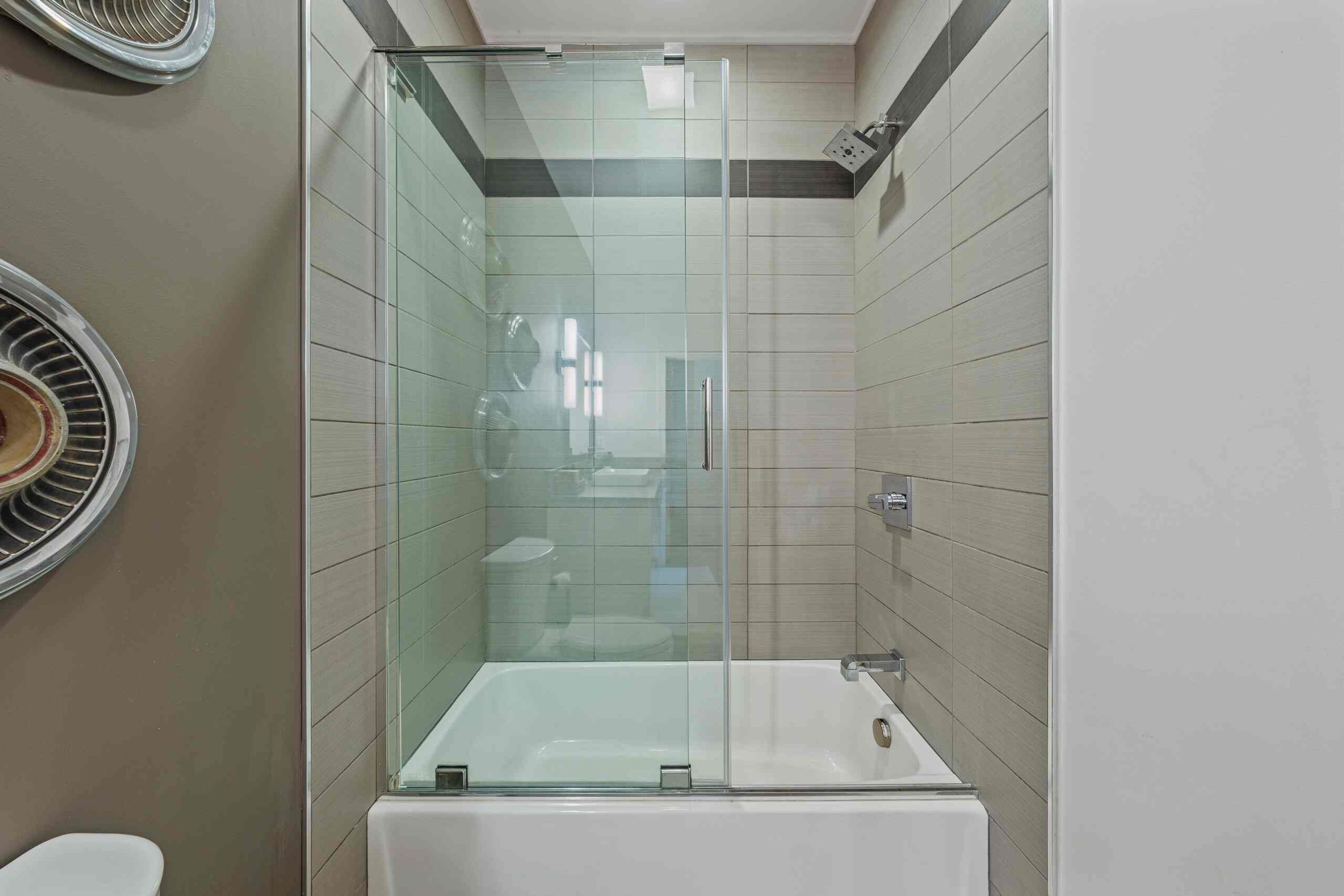 A modern bathroom with a glass-enclosed shower, a white bathtub, and a toilet.