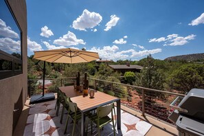 Eine Terrasse im Freien mit Tisch, Stühlen und einem großen Sonnenschirm.