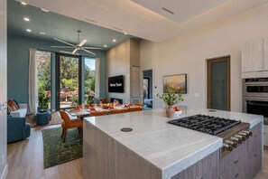 A modern kitchen with a central island, built-in oven, and a dining area with a view to the outdoors. - Bell Rock Hacienda Rooftop Deck Hot tub Sauna (Sedona)