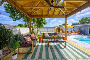 Ein überdachter Außenbereich mit Pool, Liegestühlen und einer Holzterrasse.