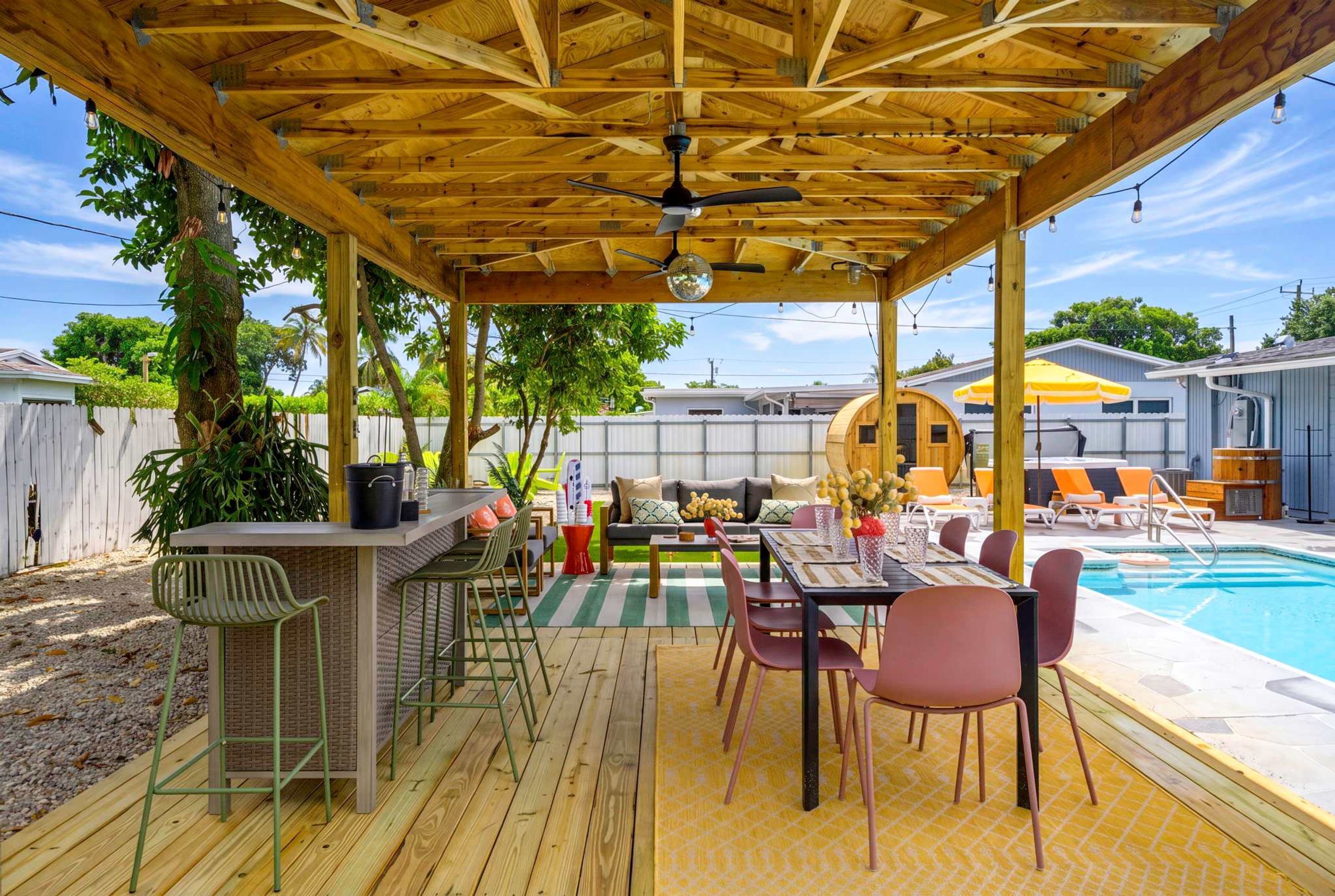 A covered outdoor patio with a pool, wooden deck, and seating area.