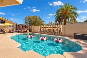 A swimming pool with lounge chairs and umbrellas, surrounded by palm trees and a desert-themed mural. - Heatwave Hideaway Pool Pickleball Games (Tempe)