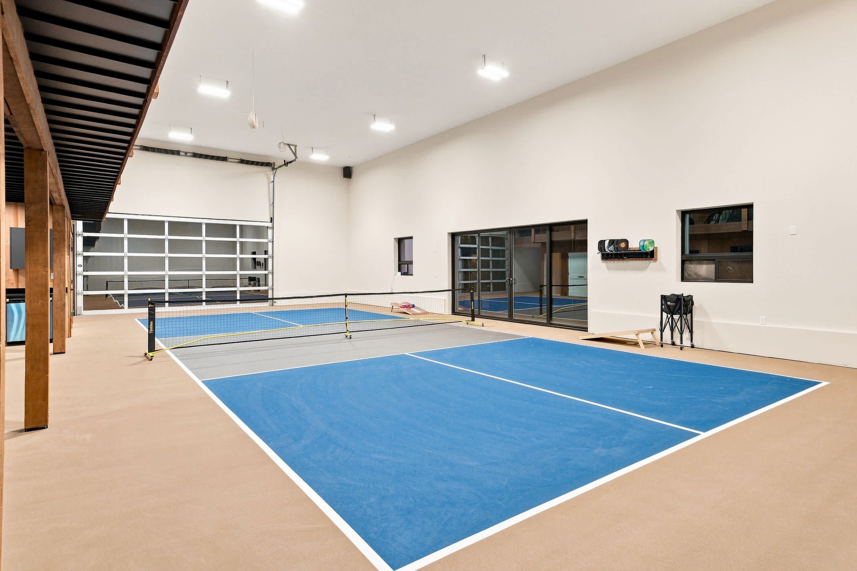 An indoor tennis court with a net, walls, and a door.