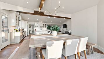A modern kitchen with white cabinetry, a central island, and a dining area with a large table and chairs.