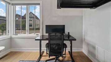 A modern room with a large window, a flat-screen TV, a black office chair, and a small table.