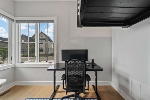 A modern room with a large window, a flat-screen TV, a black office chair, and a small table. - High Country Club Modern Mountain Escape (Deep Gap)