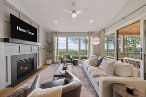 A modern living room with a fireplace, a flat-screen TV, a sofa, and a view of the outdoors. - High Country Club Modern Mountain Escape (Deep Gap)