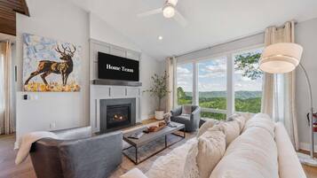 A modern living room with a fireplace, a sofa, a coffee table, and a painting of a deer.