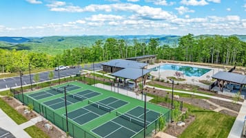 A tennis court complex with multiple courts, a pool, and a pavilion.