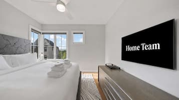 A modern hotel room with a large bed, a flat-screen TV, and a view of the outdoors.