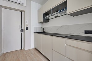 A modern kitchen with a black countertop, beige cabinets, a marble backsplash, and a built-in shelf above the sink. - Sublime  appartment  in center of Paris (Paris)