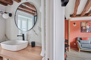 Ein Badezimmer mit einem großen, ovalen Waschbecken, einem runden Spiegel und einer Holzbalkendecke.