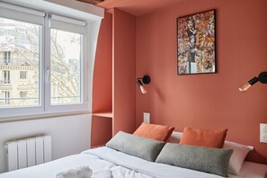 A bedroom with a bed, pillows, a window, and a wall-mounted artwork. - Charming Studio Center of Paris-Montorgueil (Paris)
