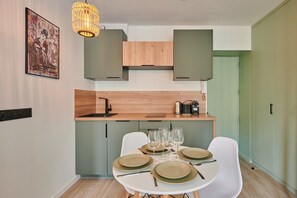 A modern kitchen with a dining table set for four, a hanging light fixture, and a green cabinet. - Charming Studio Center of Paris-Montorgueil (Paris)
