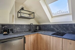 Una cocina con encimera de mármol negro, armarios de madera, horno empotrado y un tragaluz.