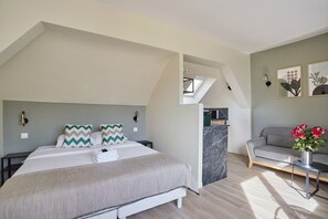 Ein Schlafzimmer mit einem Bett, einem Schlafsofa, einem kleinen Tisch und einem an der Wand befestigten Regal.