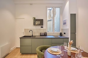 A modern kitchen with a sink, a Bosch microwave, and a window with a view of the street. - Elegant Renovated Apartment - Center of Paris (Paris)
