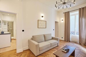 A modern living room with a sofa, a coffee table, and a bookshelf. - Elegant Renovated Apartment - Center of Paris (Paris)