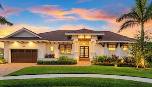 A two-story house with a well-maintained lawn, a garage, and a front entrance with a door. - Luxe Waterfront 4 Bed Escape | Near Beach (Marco Island)