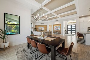 A spacious dining area with a dark wooden table, brown leather chairs, and a chandelier. - Luxe Waterfront 4 Bed Escape | Near Beach (Marco Island)
