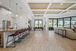 A modern kitchen with a central island, bar stools, and pendant lighting. - Luxe Waterfront 4 Bed Escape | Near Beach (Marco Island)
