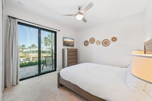 A bedroom with a bed, a ceiling fan, a view of palm trees and a body of water through a sliding glass door, and a wall with decorative plates. - Luxe Waterfront 4 Bed Escape | Near Beach (Marco Island)