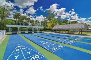 A shuffleboard court with numbered scoring areas, a covered seating area, and a thatched-roof structure. - Waterfront Bonita Springs Retreat with Boat Dock & Estero Bay & Gulf Access (Bonita Springs)
