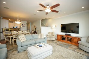 Ein Wohnzimmer mit Sofa, Hocker, Fernseher und Deckenventilator.