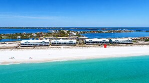 Ein Hotel an der Küste mit mehreren Gebäuden, einem Strand und einem Pier, der ins Wasser ragt.