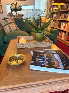 Ein Holztisch mit einer Ablage, einer Kerze, einem Blumentopf und einer Zeitschrift.