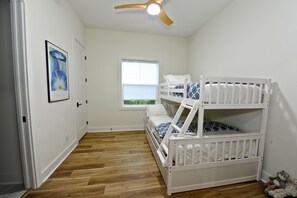 Una habitación con literas, una ventana con vistas y un ventilador de techo.