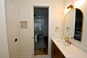 A bathroom with a white vanity, a gold-framed mirror, and a motivational quote on the wall. - Downtown Bungalow ~ 3BR 3.5BA Home, New Build, Private Yard (Fernandina Beach)