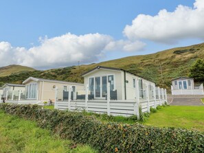 A row of mobile homes with large windows and a grassy area in front. - Frontline Sea View : P1 Whilk Meadow Caravan Park (Girvan)