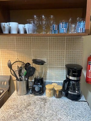Eine Küchenarbeitsplatte mit Mixer, Kaffeemaschine und verschiedenen Küchenutensilien.