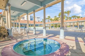 Un área de piscina con jacuzzi, sillas de descanso y un patio cubierto con columnas.