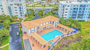Ein Hotel mit Schwimmbad, mehreren Balkonen und einem Parkplatz.