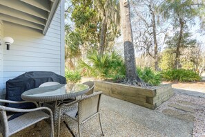 Un área de estar al aire libre con mesa y sillas, rodeada por un patio de grava y una jardinera de madera.