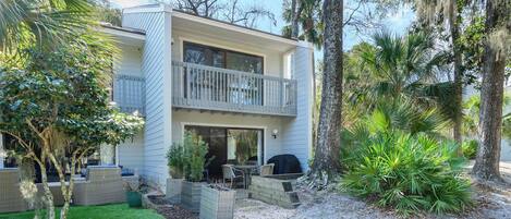 A two-story house with a balcony, outdoor seating, and a well-maintained garden.