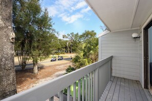 A balcony with a view of a golf course, trees, and a clear sky. - Sunset Rentals | Shipmaster 601 (Hilton Head Island)