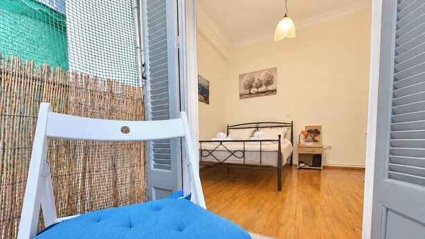 Quarto com cama, poltrona, escrivaninha e luminária pendente.