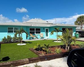 Un immobile residenziale con un prato curato, un patio con mobili da esterno e un garage.
