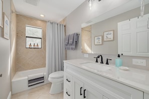 Un bagno moderno con vasca, servizi igienici e lavabo con un ampio specchio.