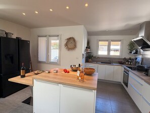 Eine moderne Küche mit einer zentralen Kochinsel, integrierten Geräten und Blick ins Freie.